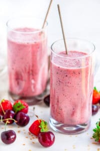 Summer Cherry Strawberry Smoothie two glasses on white marble with silver spoons