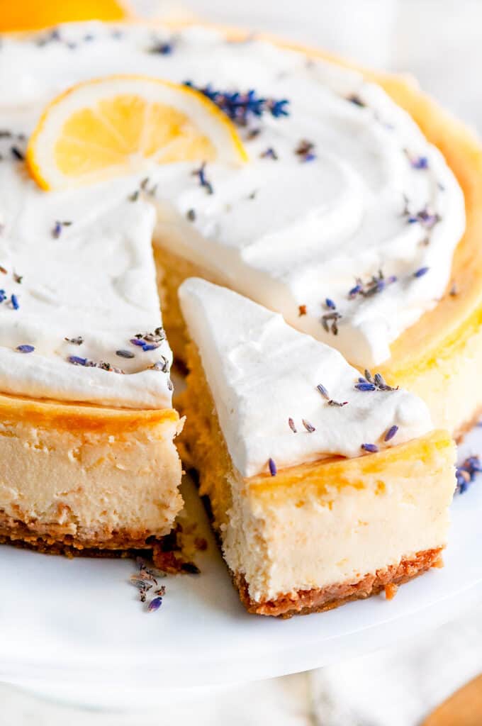 Lemon Lavender Mascarpone Cheesecake on white cake stand with slice