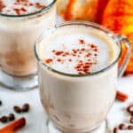 Pumpkin Spice Latte (with real pumpkin!) in glass mugs with coffee beans on white marble