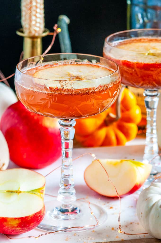 Autumn Apple Cider Whiskey Cocktail in glasses white marble with pumpkins