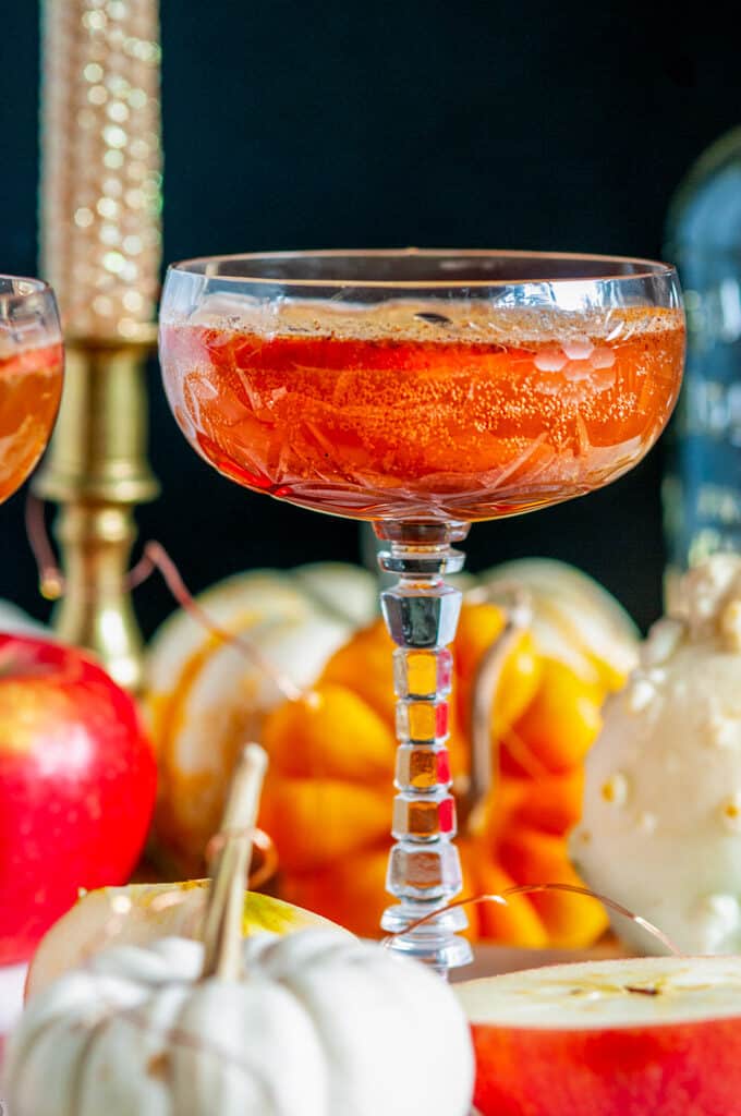 Autumn Apple Cider Whiskey Cocktail in glasses white marble with pumpkins close up