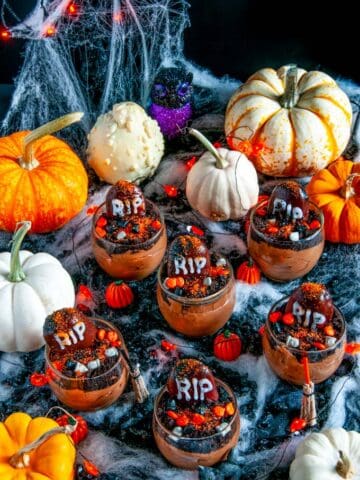 Death By Chocolate Mousse Graveyard Pots in glass on black fabric with spider webbing and pumpkins