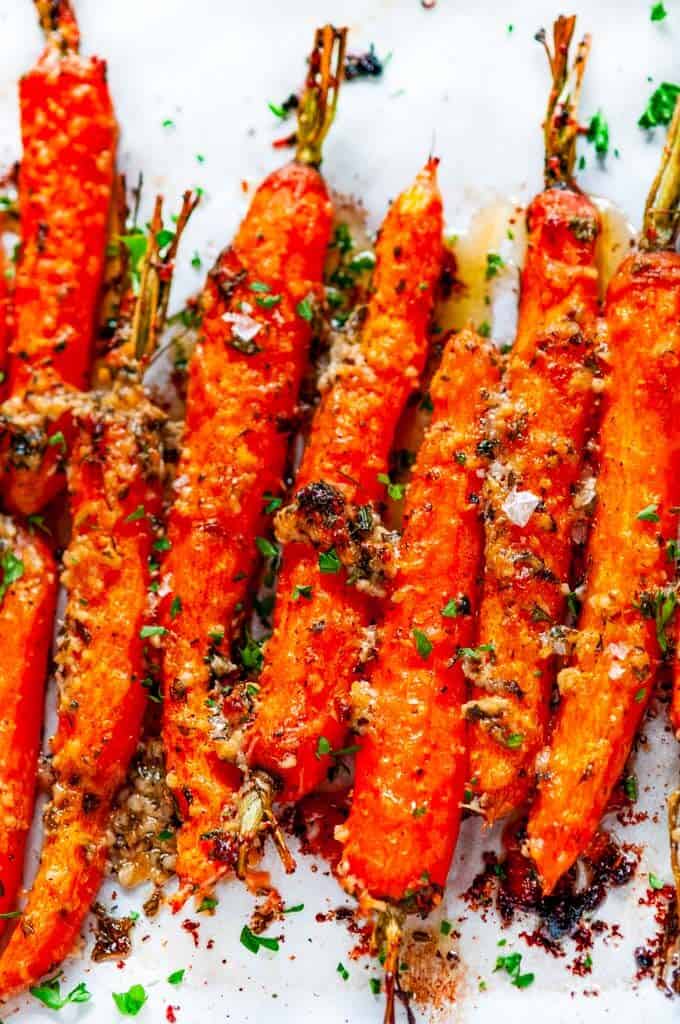 Garlic Parmesan Roasted Carrots with fresh parsley on parchment paper close up