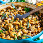 One Pot Spicy Sausage Pumpkin Pasta in blue le creuset braiser with gray wooden spoon