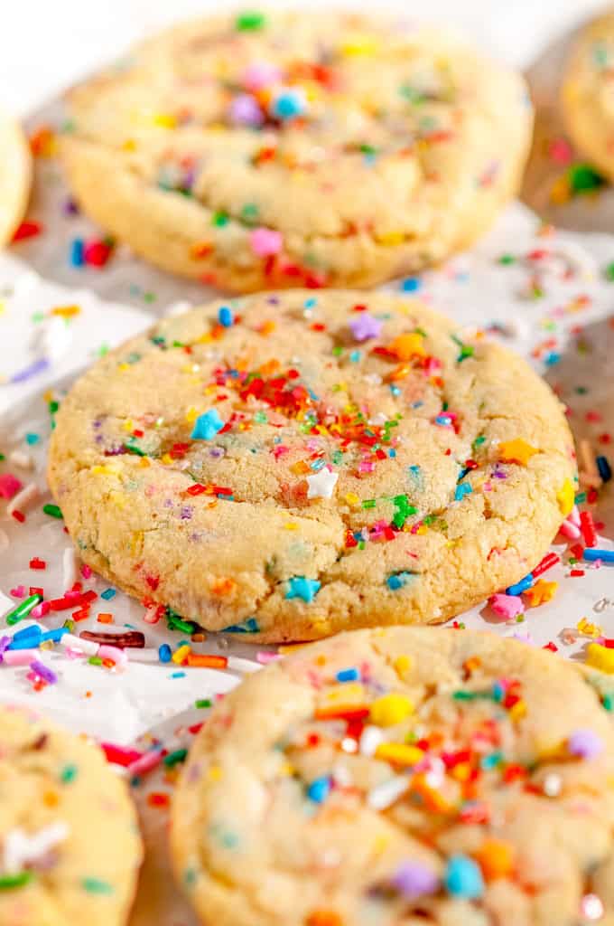 Soft Chewy Funfetti Cookies with rainbow sprinkles and sanding sugar on parchment paper close up