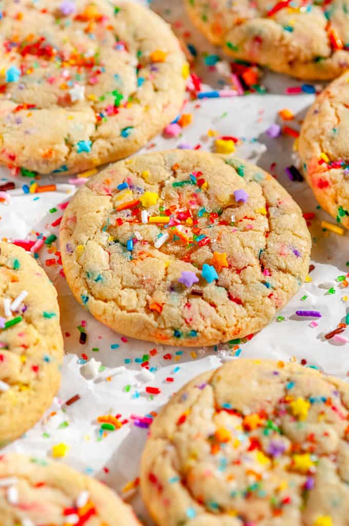 Soft Chewy Funfetti Cookies with rainbow sprinkles and sanding sugar on parchment paper