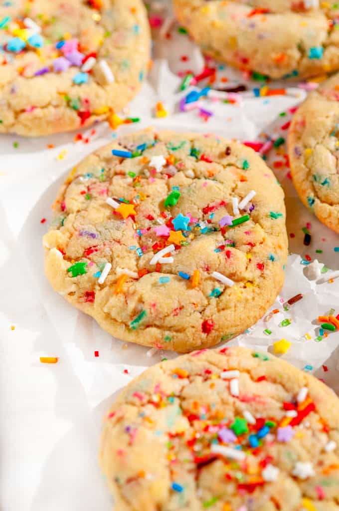 Soft Chewy Funfetti Cookies with rainbow sprinkles and sanding sugar on parchment paper