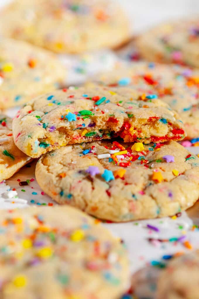 Soft Chewy Funfetti Cookies with rainbow sprinkles and sanding sugar on parchment paper half piece