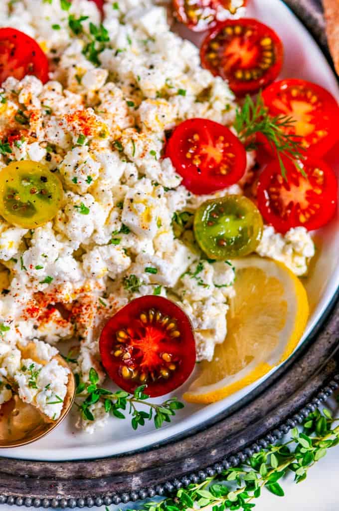 Easy Crumbled Feta Cheese Dip with cherry tomatoes lemon and thyme on white plate close up