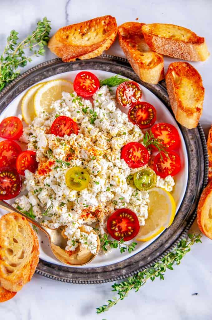 Easy Crumbled Feta Cheese Dip with cherry tomatoes lemon thyme and gold spoon on white plate