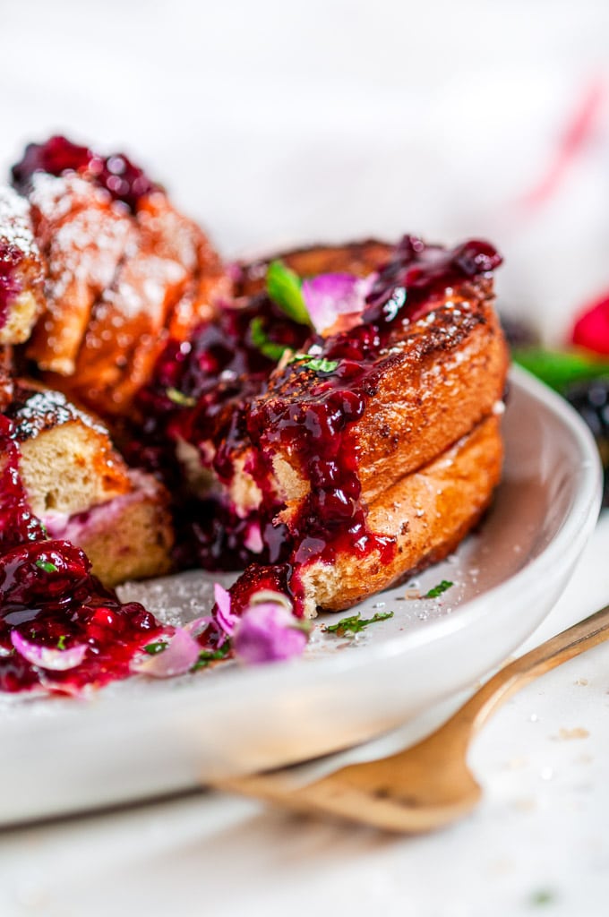 Cream Cheese Stuffed Blackberry Compote French Toast on gray plate with flowers and gold fork close up