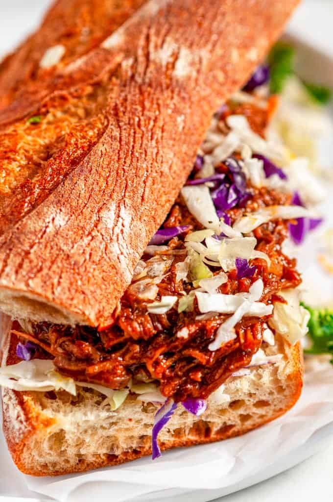 Instant Pot Pulled Pork Sandwiches on baguette with coleslaw mix on gray plate and white marble close up