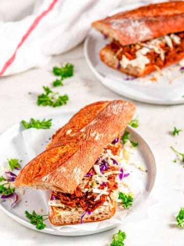 Instant Pot Pulled Pork Sandwiches on baguette with coleslaw mix on gray plate and white marble