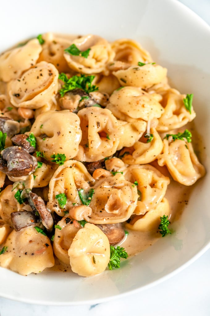 One Pot Creamy White Bean Tortellini with mushrooms and in white bowl close up