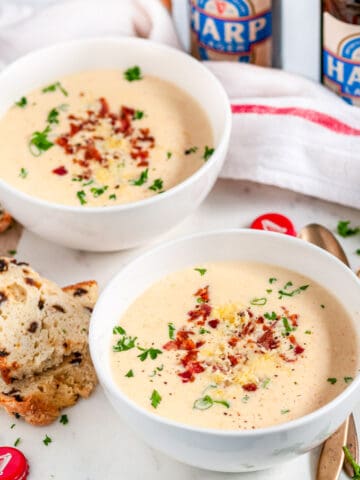 Irish Cheese Beer Soup in white bowls with gold spoons and soda bread on marble