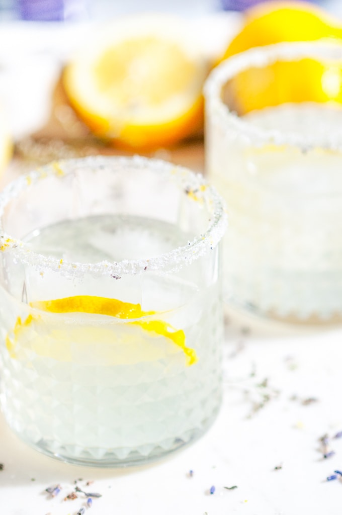 Lavender Collins Cocktail with lemons on white marble close up