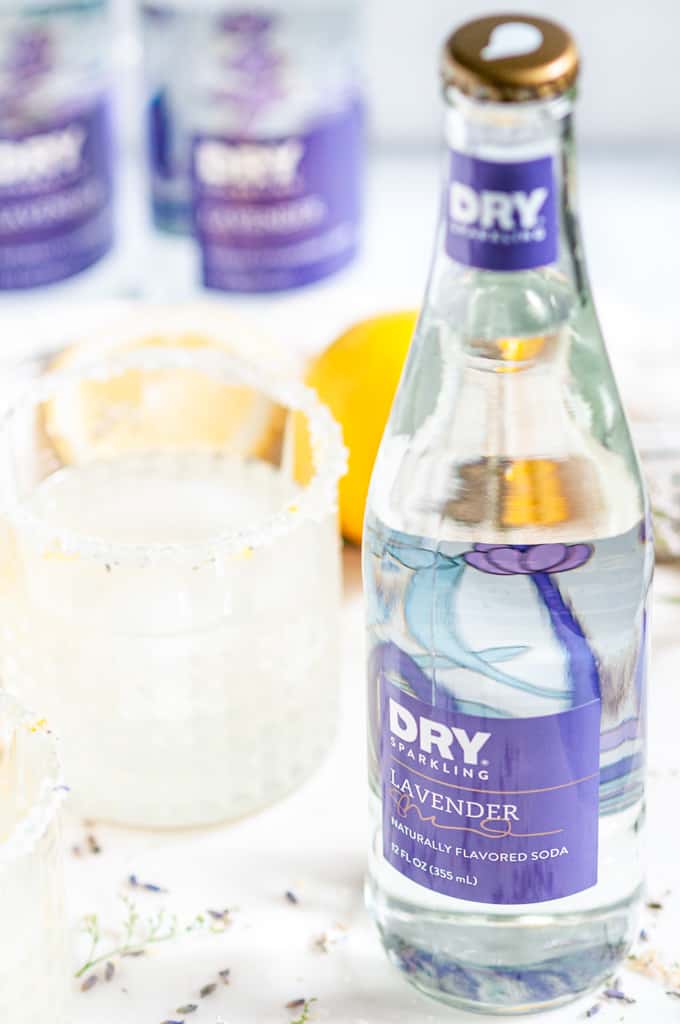 Lavender Collins Cocktail soda bottle close up on white marble with drinks