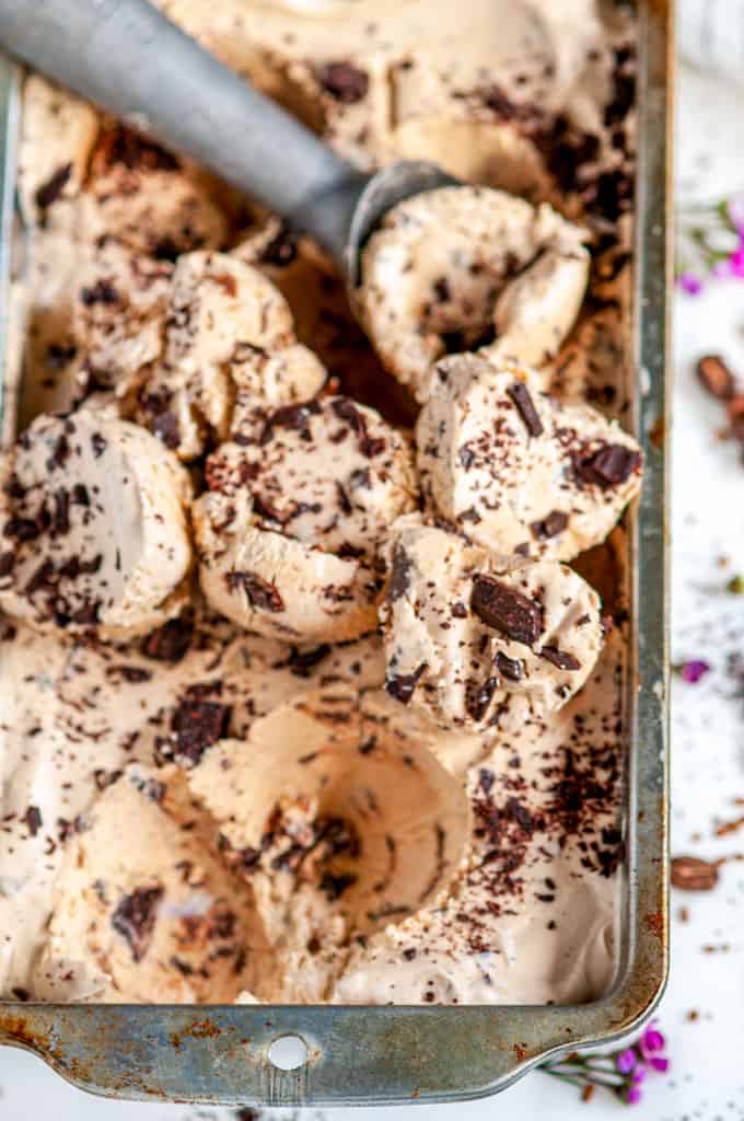 No Churn Chocolate Chunk Coffee Ice Cream with scoop on white marble with flowers close up
