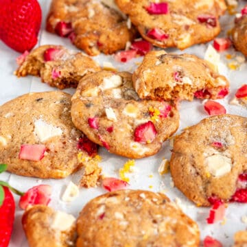 White Chocolate Strawberry Rhubarb Cookies on white parchment and marble with lemon zest close up