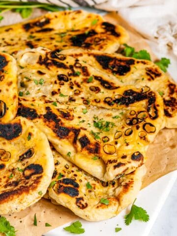 Easy Homemade Naan Bread with cilantro and tea towel on white marble and parchment