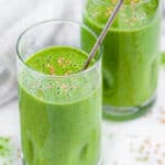 Green Tea Matcha Smoothie in tall glasses with flax seeds and silver spoons over head side view