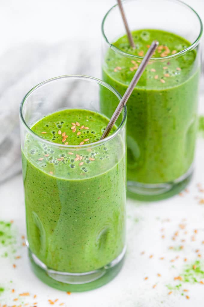 Green Tea Matcha Smoothie in tall glasses with flax seeds and silver spoons over head side view