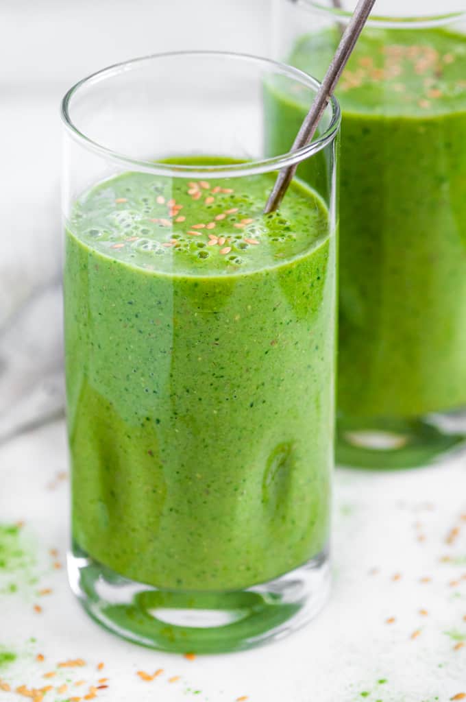 Green Tea Matcha Smoothie in tall glasses with flax seeds and silver spoons side view
