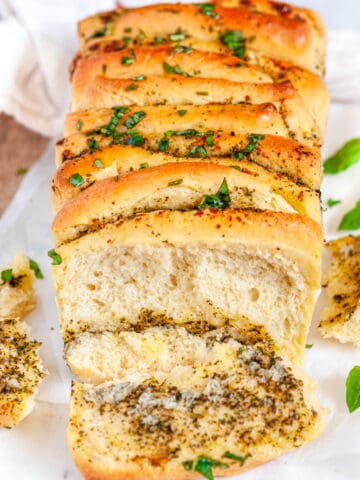 Pull Apart Pesto Bread one slice cut with basil on wood and white marble board