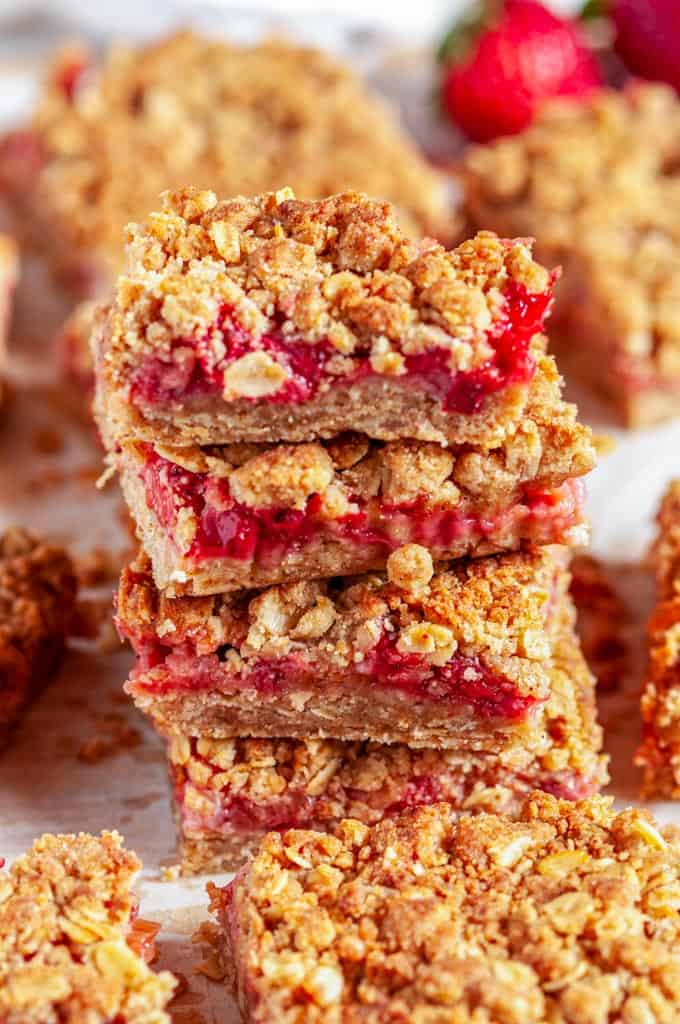 Strawberry Rhubarb Crumble Bars on parchment and white marble sliced tower close up