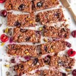 Chocolate Cherry Coconut Granola Bars on parchment with gold knife over head