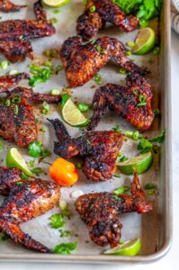 Jamaican Jerk Chicken Wings (Air Fryer + Oven Baked Methods) on sheet pan with limes and habanero pepper close up over head
