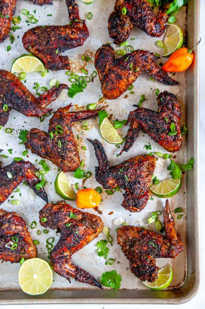 Jamaican Jerk Chicken Wings (Air Fryer + Oven Baked Methods) on sheet pan with limes and habanero pepper over head
