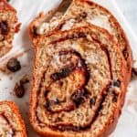 Cinnamon Raisin Swirl Bread sliced with butter and gold knife on white marble close up