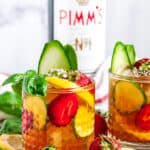 Classic Pimm's Cup Cocktail with lemon, cucumber, and strawberry slices garnished with basil leaves in glasses side view