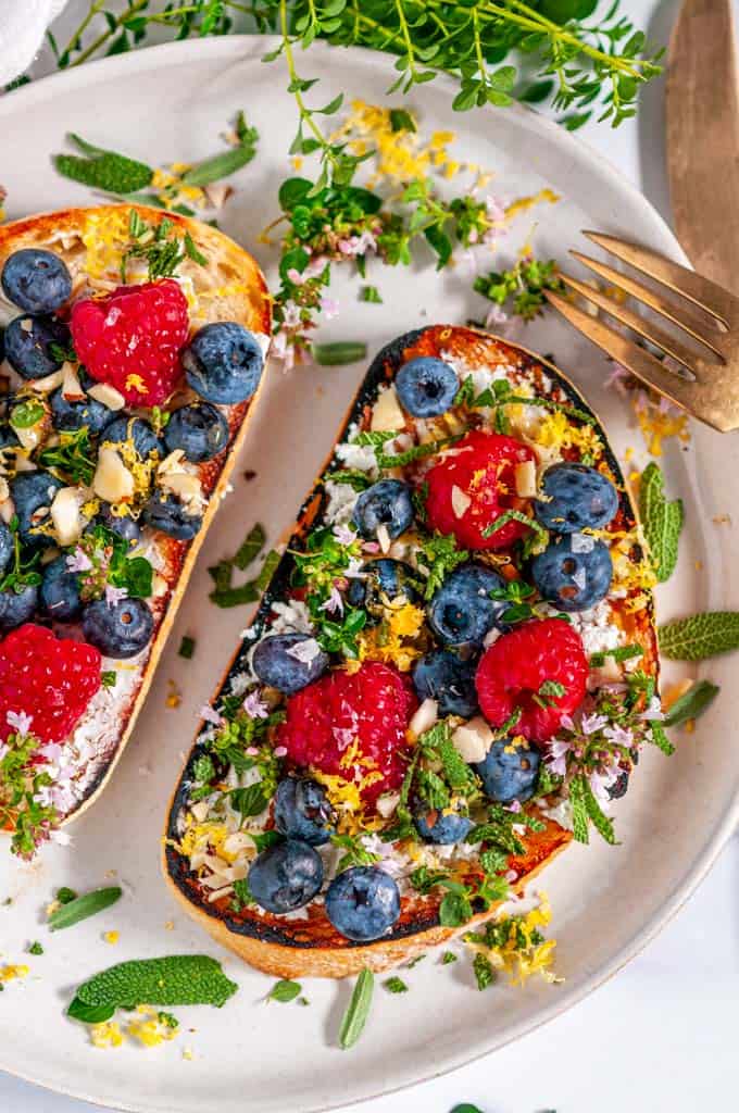 Lemon Berry Breakfast Toast with fresh herbs on gray plate with tea towel and gold utensils over head view close up