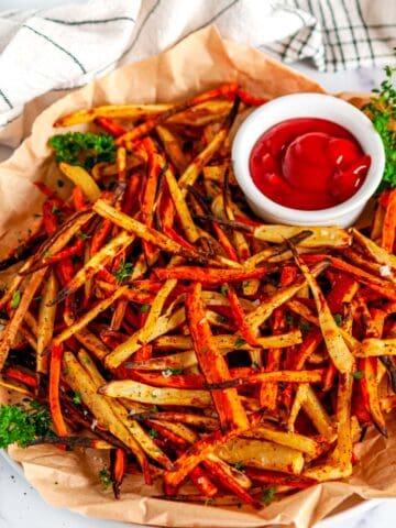 Sheet Pan Sweet Potato Fries with ketchup and parsley on brown parchment paper