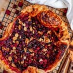 Autumn Cranberry Almond Galette on black wire rack with tea towel and copper silverware