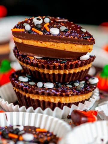 Dark Chocolate Peanut Butter Cups (Halloween Style!) with stack with sprinkles in white muffin liners and tray close up