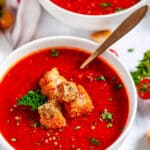 Roasted Bell Pepper Tomato Soup with croutons, parsley and gold spoons in white bowls