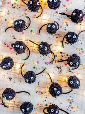 Soot Sprite Chocolate Truffles (Spirited Away) with colored star sprinkles on parchment backlit with twinkle lights