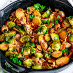 Creamy Skillet Brussels Sprouts and Mushrooms in cast iron skillet with tea towel on white marble
