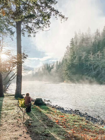 Give Thanks (Out of the Kitchen) Blond Woman Sitting in Camping Chair by Mountain River