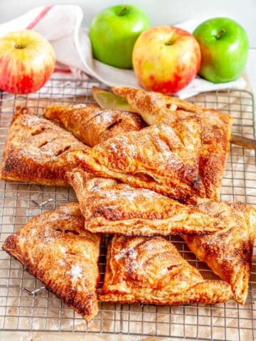 Puff Pastry Apple Turnovers on silver wire rack with white towel