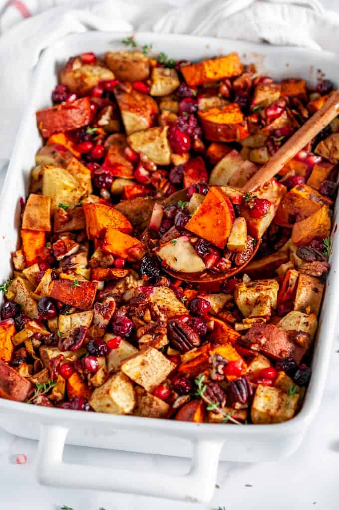 Sweet Potato Cranberry Casserole in white baking dish with wooden spoon on marble