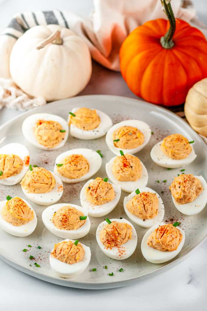 Thanksgiving Pumpkin Deviled Eggs with chives on gray plate and white marble