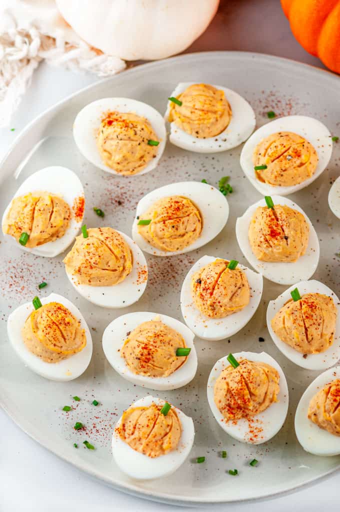 Thanksgiving Pumpkin Deviled Eggs with chives on gray plate and white marble