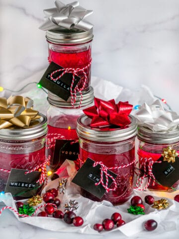 Boozy Cranberry Sauce Gift Jars with ribbon and gift tags on tissue paper and white marble