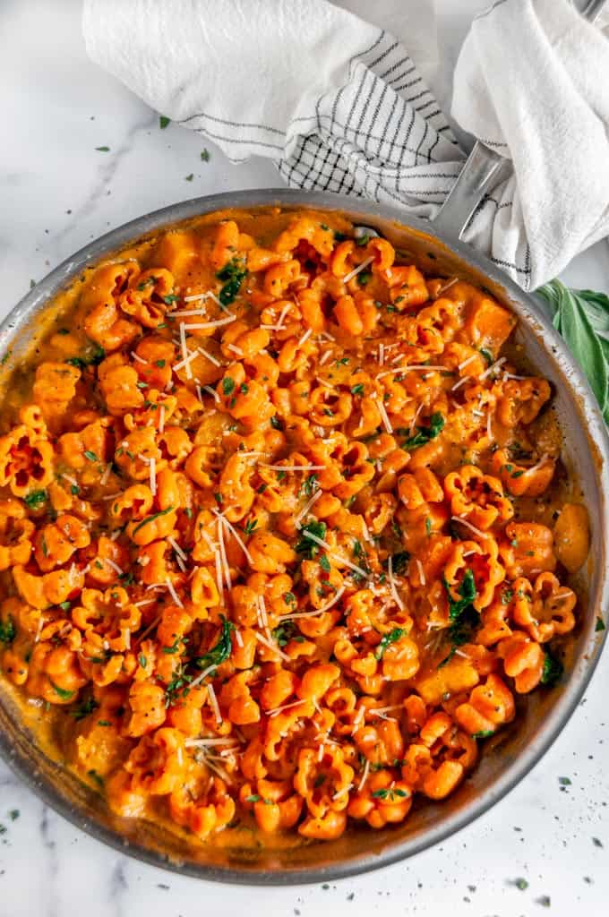 Creamy Butternut Squash Pasta in silver All-Clad skillet with fresh sage on white marble