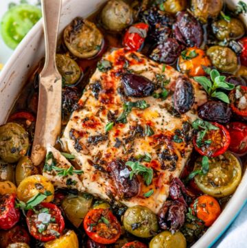 Easy Mediterranean Baked Feta in small blue baking dish with cherry tomatoes and kalamata olives