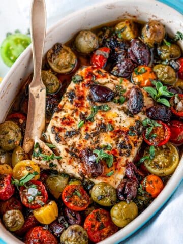 Easy Mediterranean Baked Feta in small blue baking dish with cherry tomatoes and kalamata olives